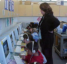 a row of children with headsets using computers at the Firebaugh Community Technology Collaborative