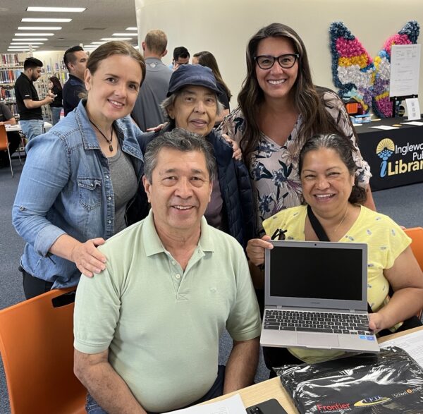 230422_Inglewood_Public_Library_GCCA_enrollmentday - Copy a family of five adults who have just been the recipients of new laptop smiling for a photograph with their new computer.